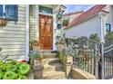 Inviting front entry with wooden door, potted plants, and steps, surrounded by a black metal fence at 312 President St, Charleston, SC 29403