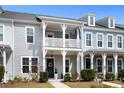 Charming townhouse with a second-story porch, and black front door with nice landscaping at 3125 Sturbridge Rd, Mount Pleasant, SC 29466