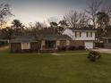 Dusk shot of a two-story brick home with a well-manicured front lawn, trees, and attached one car garage at 760 Royle Rd, Ladson, SC 29456