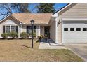 Close up of a charming one-story home with manicured lawn, garage, and inviting front entry at 101 Danzid Dr, Summerville, SC 29483