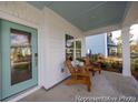 Inviting front porch features an aqua-colored door, comfortable seating, and a blue-painted ceiling at 1054 Marsh Harrier Dr # Cc3-15-5P, Ravenel, SC 29470