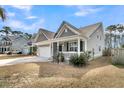 Inviting gray home featuring a covered front porch and a manicured lawn with palm tree at 225 Waning Way, Charleston, SC 29492