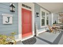 Cozy front porch with a red door, table and chairs, and stylish décor creating a warm welcome at 3676 Shutesbury St, Mount Pleasant, SC 29466