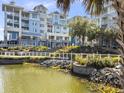Charming multi-story condo building with pond view, well-manicured landscaping, and coastal architectural details at 5802 Palmetto Dr # B-202, Isle of Palms, SC 29451