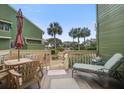 Relaxing deck with wood table and chairs, a lounger, and scenic views of palm trees and other condos at 7000 Palmetto Dr # 5A, Isle of Palms, SC 29451
