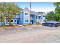 Two-story light blue condo building with a gravel parking area and dark blue SUV at 851 Sandlake Dr # F, Mount Pleasant, SC 29464