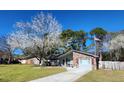 Cozy one-story home with brick accents, lush green lawn, flowering tree, and American flag at 105 Ford Ct, Summerville, SC 29483