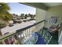 A cozy balcony with outdoor furniture overlooks palm trees and a parking lot at 1300 Ocean Blvd # 221, Isle of Palms, SC 29451