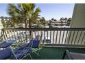 A bright balcony setting with outdoor seating offers a view of the parking lot and surrounding palm trees at 1300 Ocean Blvd # 221, Isle of Palms, SC 29451