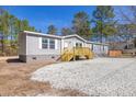 The single-story home boasts gray siding, a wooden front porch, and fresh gravel landscaping at 1326 Black Tom Rd, Moncks Corner, SC 29461