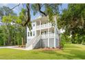 Charming two-story white home with double porches surrounded by mature trees and lush landscaping at 2151 Arthur Rose Ln, Johns Island, SC 29455