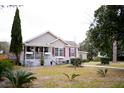 Well-maintained home with a cozy front porch, complemented by a mature tree and garden at 2590 Otranto Rd, North Charleston, SC 29406