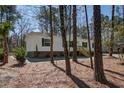 Picturesque single-story home with white siding, dark shutters, wooden stairs, and a natural wooded setting at 421 Peacock Ln, Summerville, SC 29486