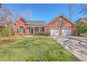 Charming brick home featuring a two-car garage, lush front lawn, and inviting front porch at 8757 E Fairway Woods Dr, North Charleston, SC 29420