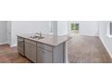 Kitchen island with gray cabinets, stainless dishwasher, granite countertop and sink in a bright open-concept living space at 7018 Deanston Dr, Ravenel, SC 29470