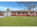 Charming red brick ranch-style home with a well-manicured lawn, black shutters, and a covered front porch at 117 Swan Dr, Summerville, SC 29485