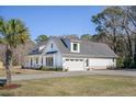 Spacious white farmhouse featuring a three-car garage, manicured lawn, and mature palm trees at 1174 Hitchfield Ln, Awendaw, SC 29429
