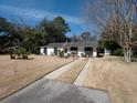 Well-maintained white brick home with a long driveway, green trees, and a spacious front yard at 1344 Pickett St, Charleston, SC 29412