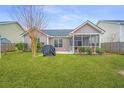 This backyard features a well maintained lawn, a grill, and a screened in patio at 140 Satur Dr, Goose Creek, SC 29445