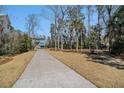 Long driveway approaching a charming two-story exterior featuring blue siding, white trim, and beautiful landscaping at 1899 N James Gregarie Rd, Mount Pleasant, SC 29466