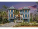 Charming two-story exterior at dusk featuring blue siding, white trim, a double garage, and beautiful landscaping at 1899 N James Gregarie Rd, Mount Pleasant, SC 29466
