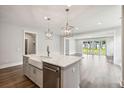 Bright kitchen with island, pendant lighting, stainless dishwasher and sink, and hardwood floors at 210 Quimby Hill Dr, Huger, SC 29450