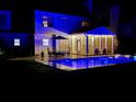 Nighttime view of a backyard with a swimming pool, lounge chairs, an outdoor table, and a screened-in porch at 2900 Colonnade Dr, Mount Pleasant, SC 29466