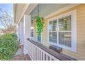 Inviting front porch featuring hanging flower baskets, stylish seating, and elegant details at 303 Crossandra Ave, Summerville, SC 29483