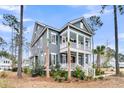 Two-story home with a covered porch and balcony, showcasing its architectural design and lush surrounding landscaping at 3851 Sawyers Island Dr, Mount Pleasant, SC 29466