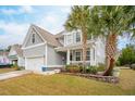 Charming home with light gray siding, two palm trees, a two car garage, and manicured lawn at 5358 Birdie Ln, Hollywood, SC 29449