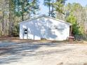 Detached single garage featuring white siding, a garage door, and an entry door at 60 Caboose Ct, Cottageville, SC 29435