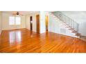 Bright living room featuring gleaming hardwood floors, a ceiling fan, and staircase with iron railing at 7 Doughty St # C, Charleston, SC 29403
