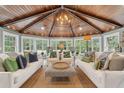 Inviting sunroom with wood paneled ceiling, white sofas, stylish pillows, and large windows overlooking the garden at 12 Broughton Rd, Charleston, SC 29407