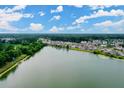 Aerial view of neighborhood homes surrounding a tranquil lake, set against a vibrant blue sky at 1216 Hammrick Ln, Johns Island, SC 29455