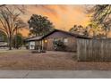 Brick home with a fenced yard, tidy landscaping and warm lighting at sunset at 7753 Linsley Dr, North Charleston, SC 29418