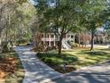Beautiful home showcasing a long driveway, mature trees, and manicured lawn at 8608 Wild Bird Ct, North Charleston, SC 29420