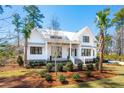 Stylish two-story house featuring a modern white facade, metal roofing, and manicured shrubbery at 105 Peninsula Dr, Ravenel, SC 29470