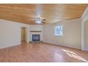 Cozy living room with a wooden ceiling, ceiling fan, fireplace, and abundant natural light through the window at 106 Mayrant St, Summerville, SC 29483
