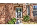 Close-up of a brick front door area with plants and decorated door wreath at 1104 Old Course Ln, Mount Pleasant, SC 29466