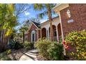 Beautiful brick home boasting a columned front porch, lush landscaping, and mature palm trees at 1407 Congressional Blvd, Summerville, SC 29483