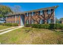 Two-story brick apartment building featuring dark shutters, lush bushes, and a well-maintained lawn at 21 Rivers Point Row Row # 17 B, Charleston, SC 29412