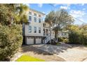 Lovely three-story home featuring a brick driveway, two-car garage, and mature tree in the landscaped yard at 4008 Cameron Blvd, Isle of Palms, SC 29451