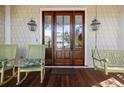 Charming front porch featuring a wooden bench swing, rocking chairs, and a decorative wooden and glass front door at 4008 Cameron Blvd, Isle of Palms, SC 29451