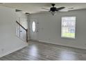 Bright living room with gray wood flooring, ceiling fan, and a white front door and staircase at 415 Aberdeen Cir, Summerville, SC 29483