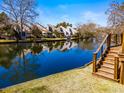 Beautiful waterfront view with a wooden staircase leading to the water and neighborhood homes in the background at 777 Lake Frances Dr, Charleston, SC 29412