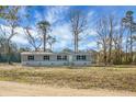 Well-maintained single-story home featuring gray siding, black shutters, and a welcoming front porch, nestled in nature at 116 Wisteria Falls Trl, Saint Stephen, SC 29479