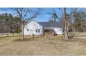 Charming home exterior with a wooden porch, surrounded by a spacious lawn and mature trees at 1677 French Santee Rd, Jamestown, SC 29453