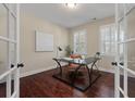 Bright home office featuring hardwood floors, plantation shutters, and a modern glass desk at 2242 Terrabrook Ln, Charleston, SC 29412