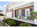Inviting front porch featuring colorful Adirondack chairs, lush plants, and charming decor at 3707 Blackjack Rd, Ladson, SC 29456