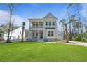 Inviting two-story home featuring a spacious lawn, palm trees, and a double front porch at 4217 Royal Harbor Rd, Hollywood, SC 29449